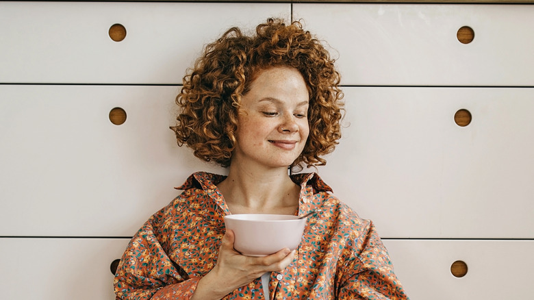 Smiling woman holding cereal bowl
