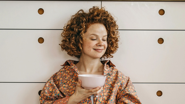 Smiling woman holding cereal bowl