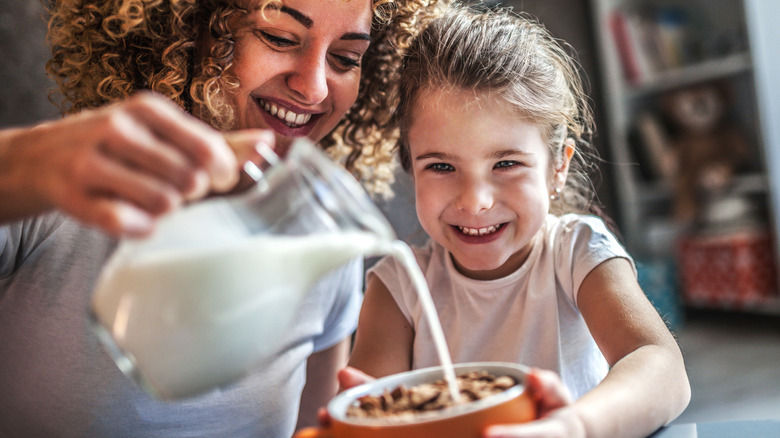 Woman pouring milk into cereal bowl
