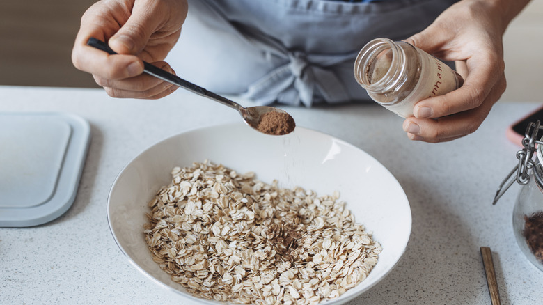 Hand sprinkling cinnamon into oatmeal