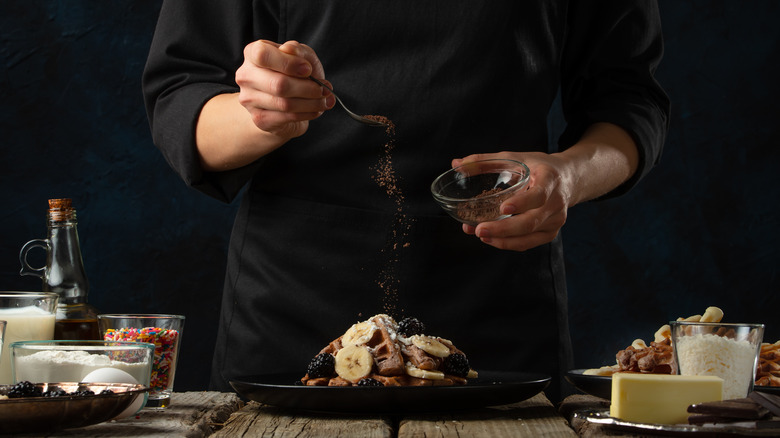 Man sprinkling cinnamon on dessert plate