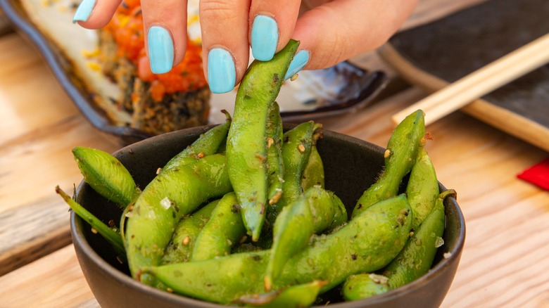 Hand picking up edamame