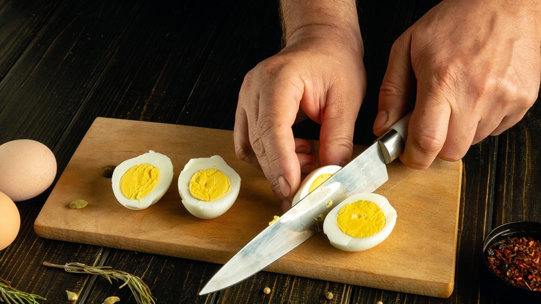 Hands slicing hard boiled eggs with knife