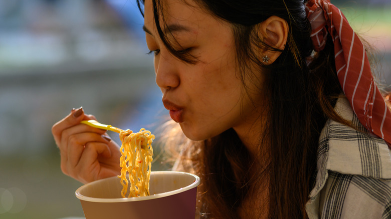 Woman eating ramen noodles outdoors