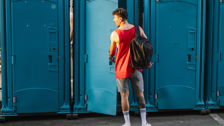 man opening port-a-potty door