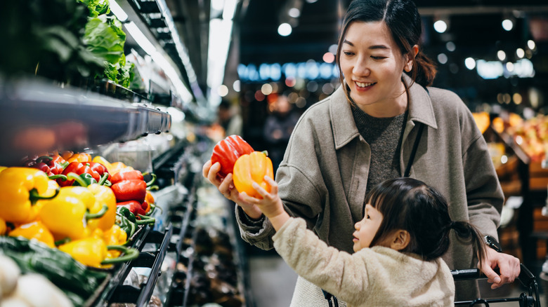 woman and toddler shopping for bell peppers