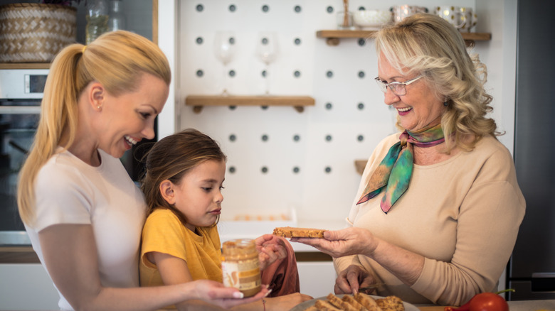 older woman sharing a peanut butter sandwich with child