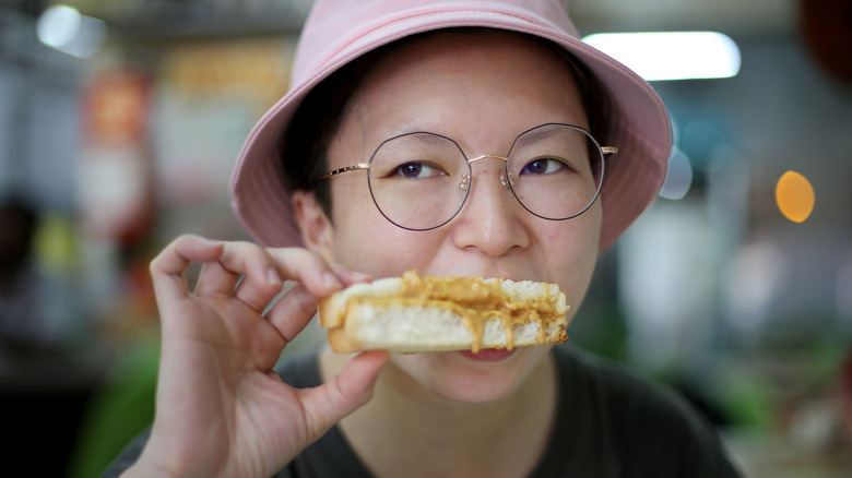 Woman eating peanut butter sandwich
