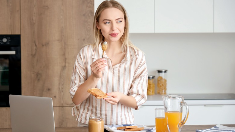 woman holding a spoon and bread with peanut butter