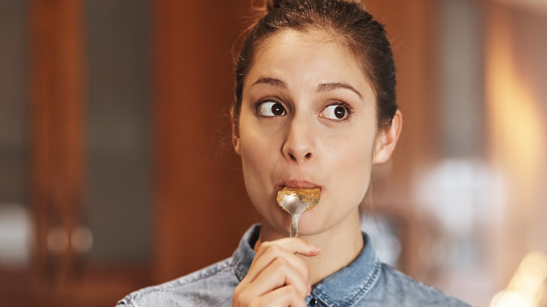 Woman eating spoonful of peanut butter