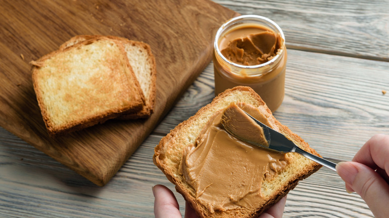 Spreading peanut butter on toast