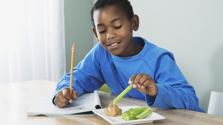 Boy dipping celery sticks in PB