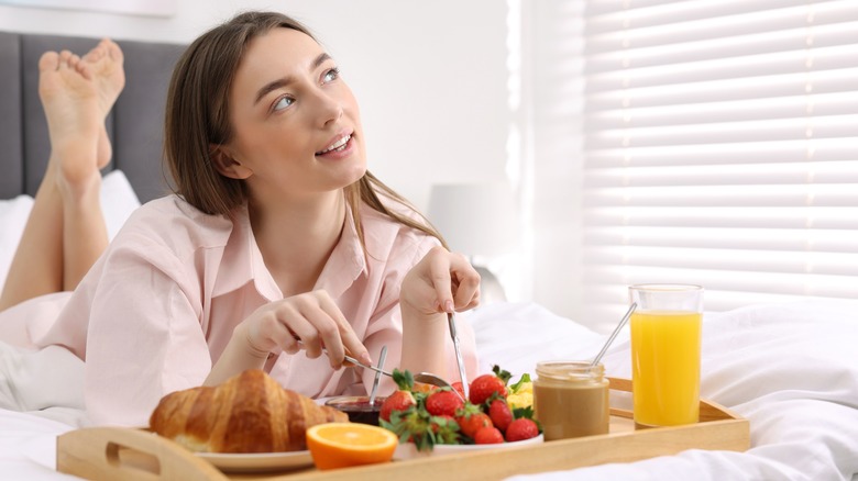 woman eating strawberries and peanut butter in bed