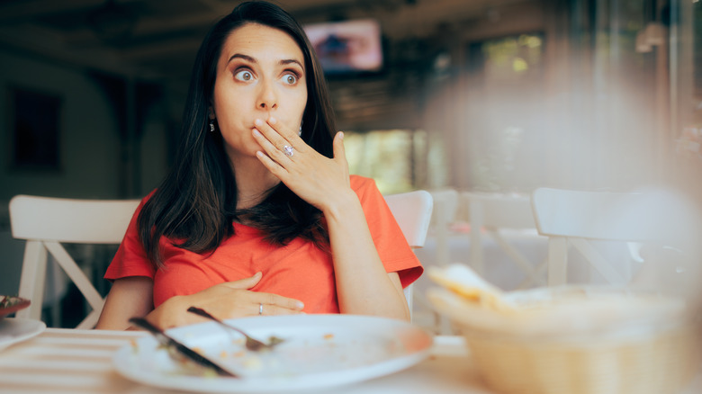 Woman at restaurant covering mouth