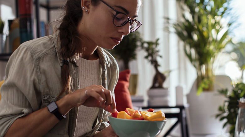 Woman eating bowl of fruit