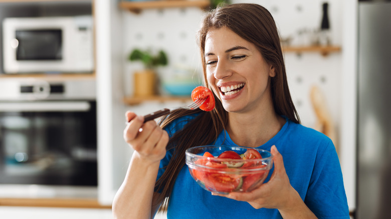 Smiling woman eating tomato