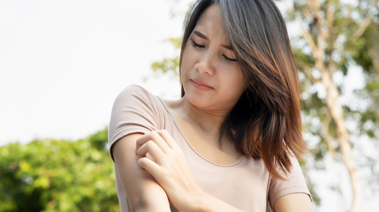 A woman scratches her arm