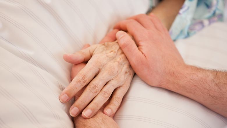 Holding someone's hand in a hospital bed