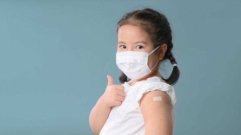 A child giving a thumbs up after getting a vaccine