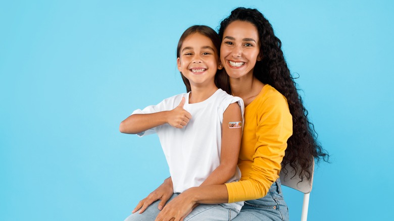 A mother holding her newly vaccinated daughter