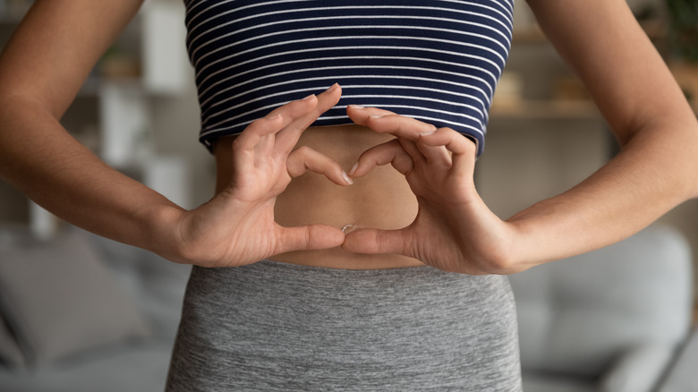 a woman smiling and holding her stomach 