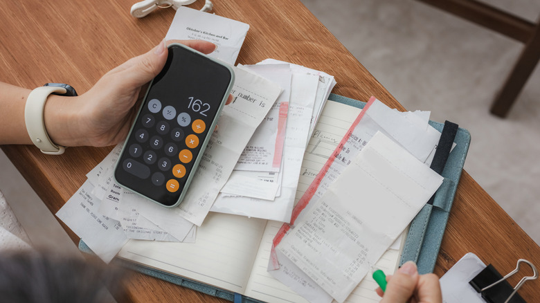 person with calculator and receipts making a budget