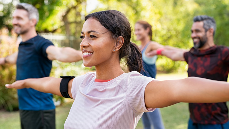 woman in the park doing yoga with others smiling