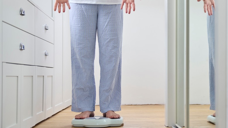 Woman on scale surprised by weight