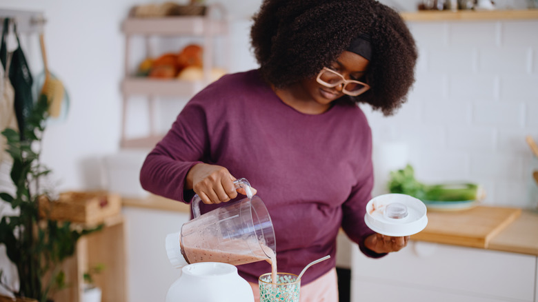 woman pouring smoothie into cup