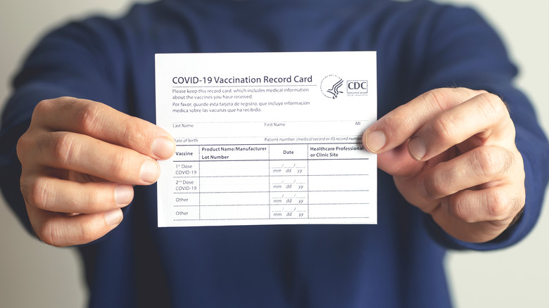 COVID-19 vaccine card displayed by two hands