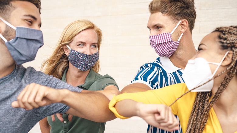 Friends in masks touch elbows