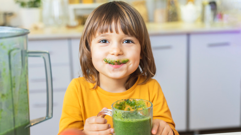 Young child drinking green smoothie