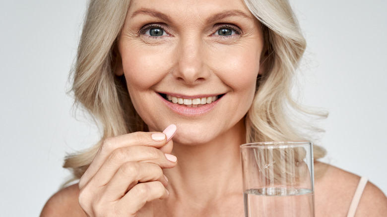 Smiling elderly woman taking magnesium tablet