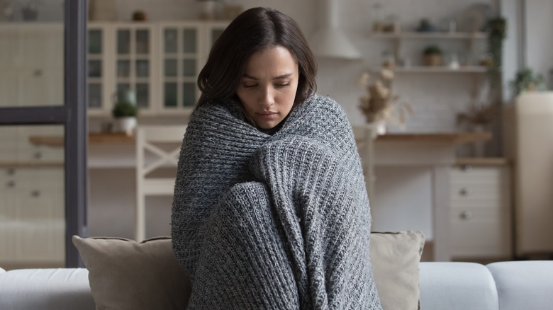 Woman in blanket on couch