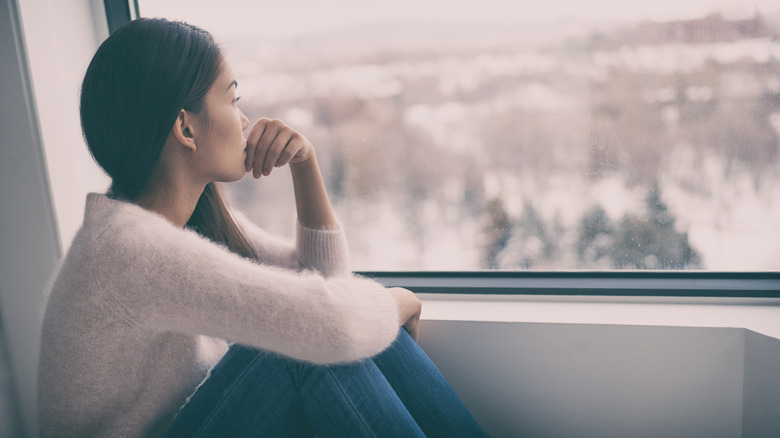 Woman with seasonal affective disorder sitting by a window