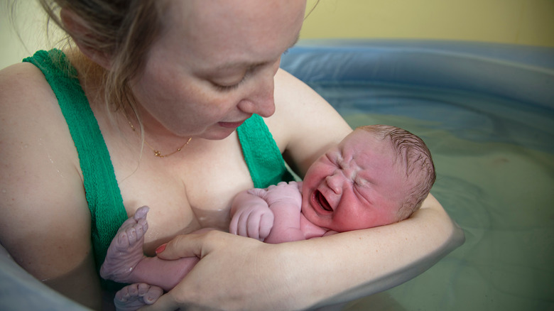 Woman holding baby in pool