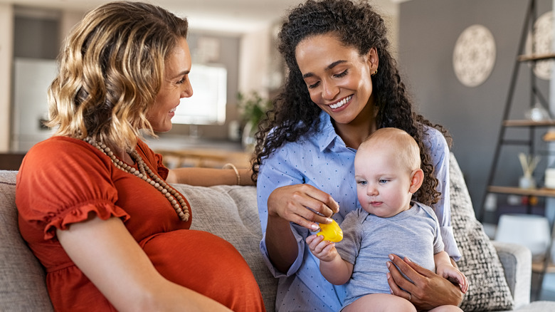 Woman holding baby beside pregnant woman