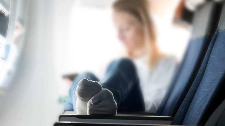 woman stretching legs on airplane