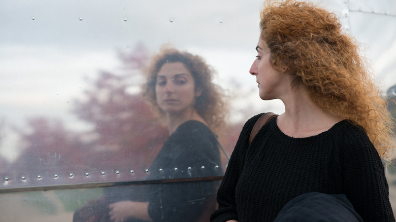 woman staring at her reflection in a window