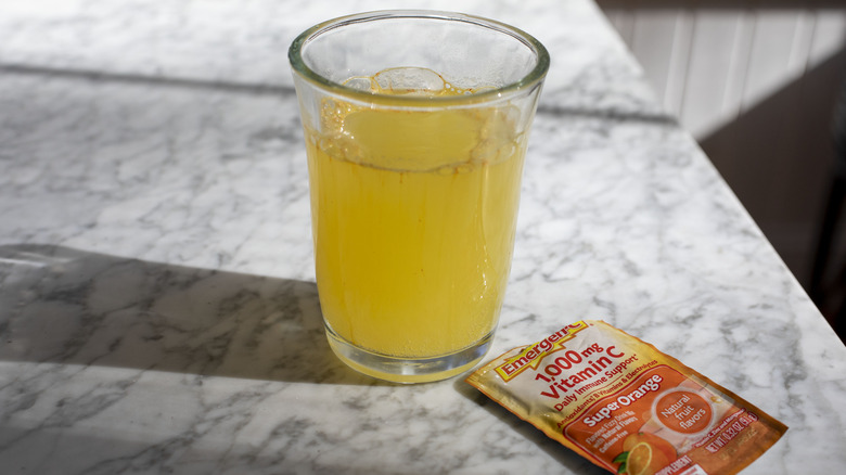 glass with orange liquid next to emergen-c packet