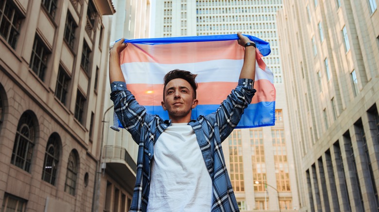 Trans man holding up a trans flag