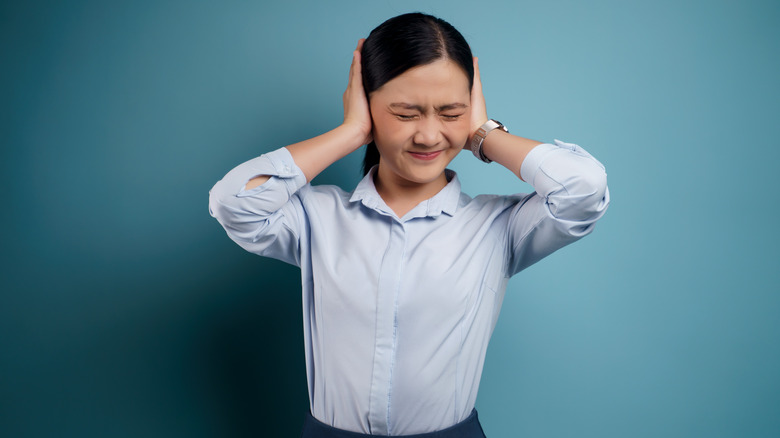 woman holding ears
