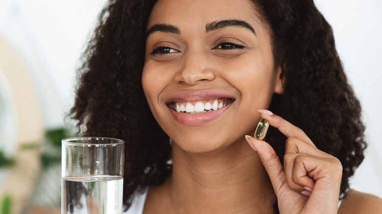 woman with capsule and glass of water