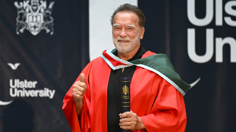 Arnold Schwarzenegger holding his honorary doctorate during a ceremony at Ulster University