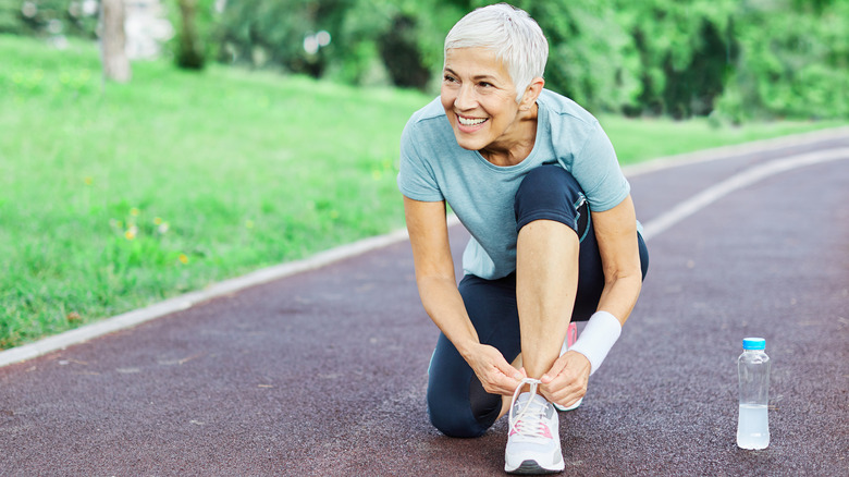 Active mature woman tying shoes