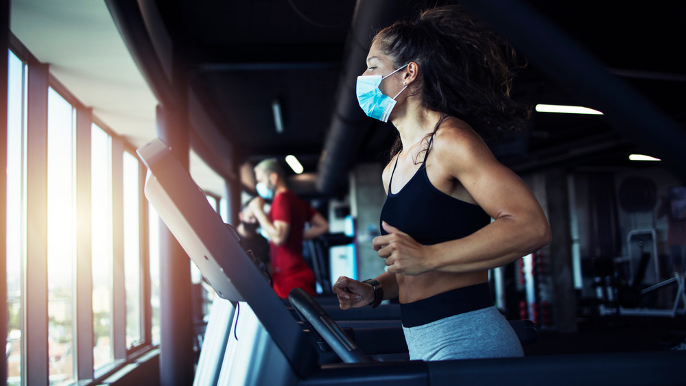 Woman wearing a face mask runs on a treadmill