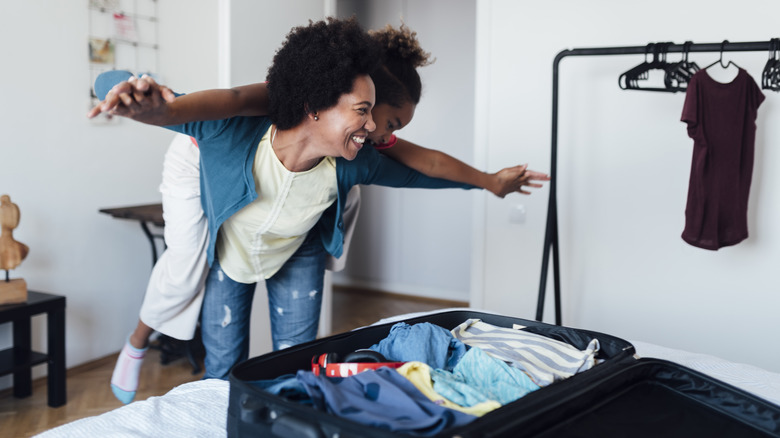 Smiling mother and child packing suitcase