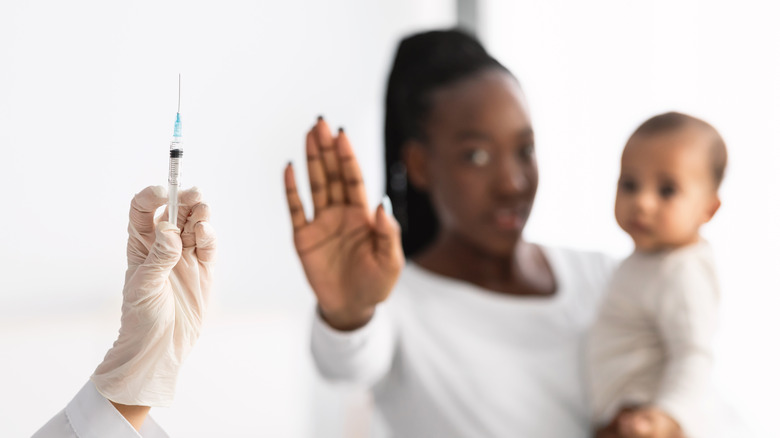 black woman holding baby refusing vaccine