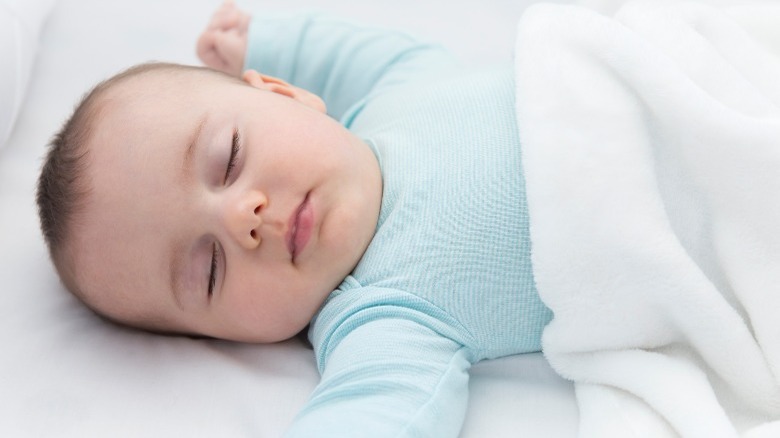baby sleeping on its back in crib