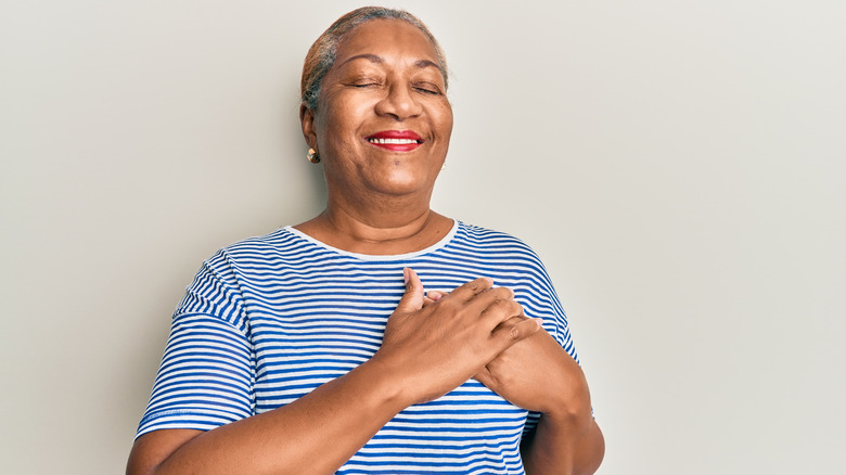 lady smiling with eyes closed and hands over heart